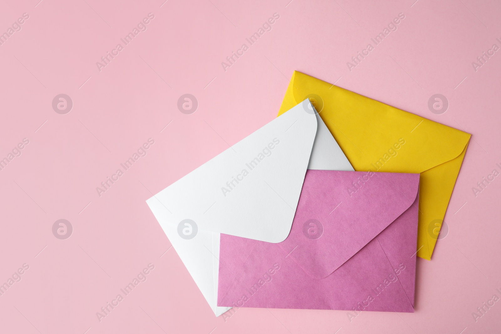 Photo of Colorful paper envelopes on pink background, flat lay