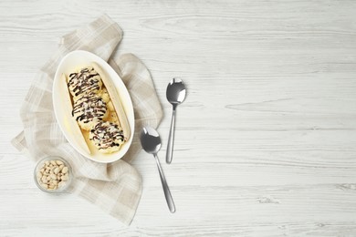 Photo of Delicious banana split ice cream on white wooden table, flat lay. Space for text