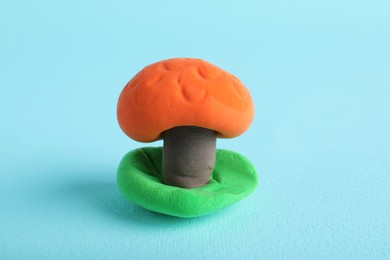 Photo of Colorful mushroom made from play dough on light blue background, closeup