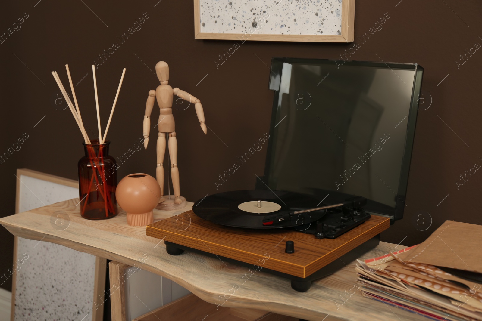 Photo of Modern turntable with vinyl disc on wooden table indoors. Interior design