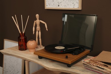 Modern turntable with vinyl disc on wooden table indoors. Interior design