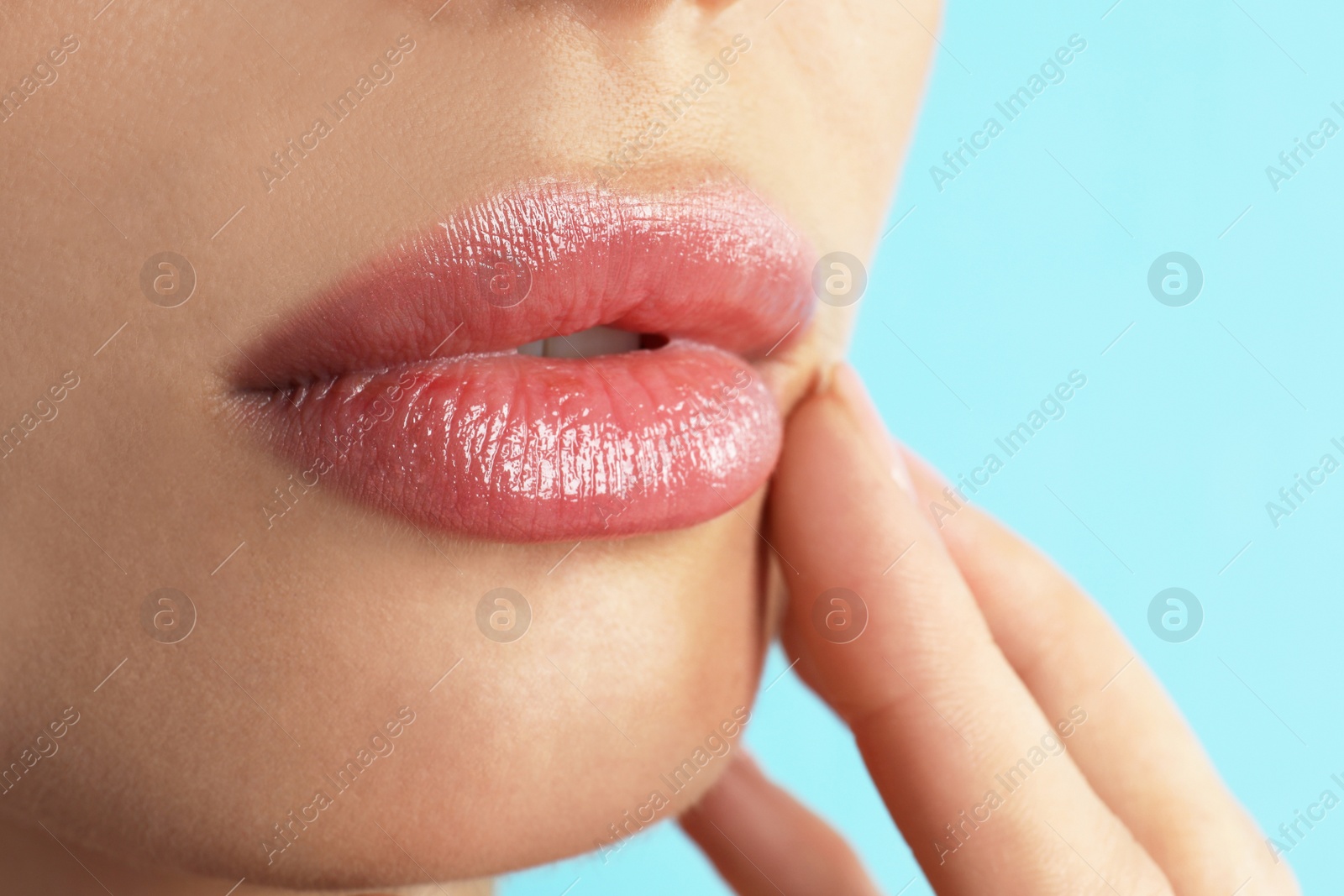 Photo of Woman with beautiful full lips on light blue background, closeup