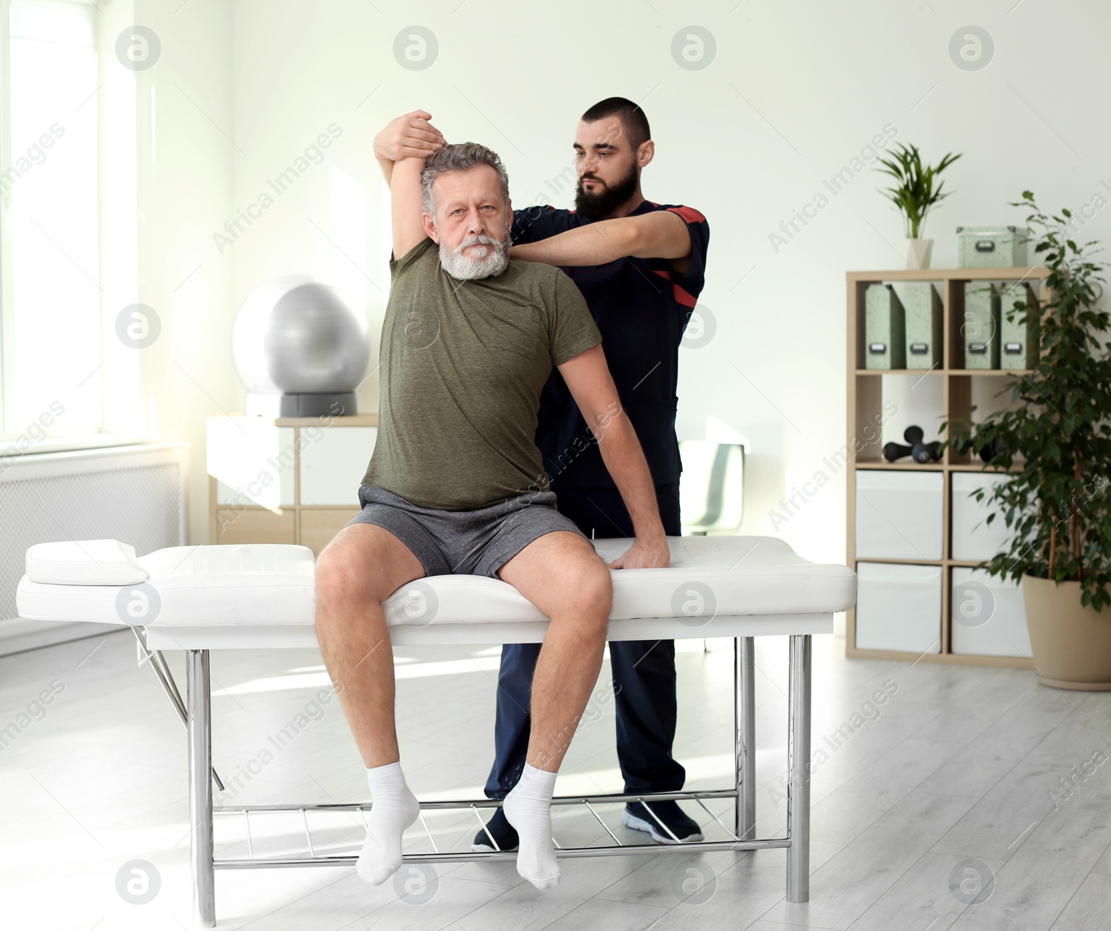 Photo of Physiotherapist working with patient in clinic. Rehabilitation therapy