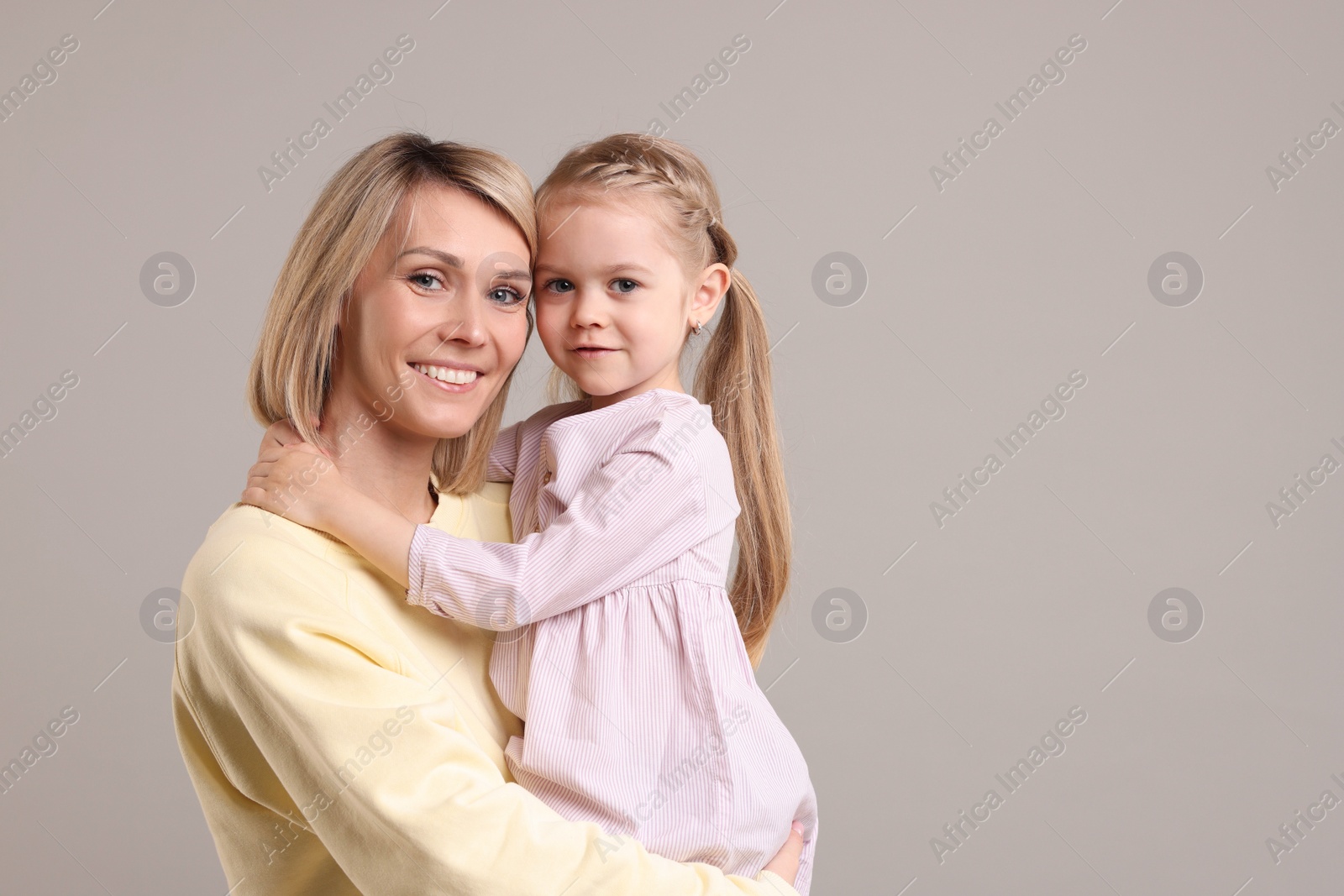 Photo of Family portrait of happy mother and daughter on grey background. Space for text