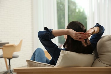 Teenage girl relaxing on sofa at home, back view