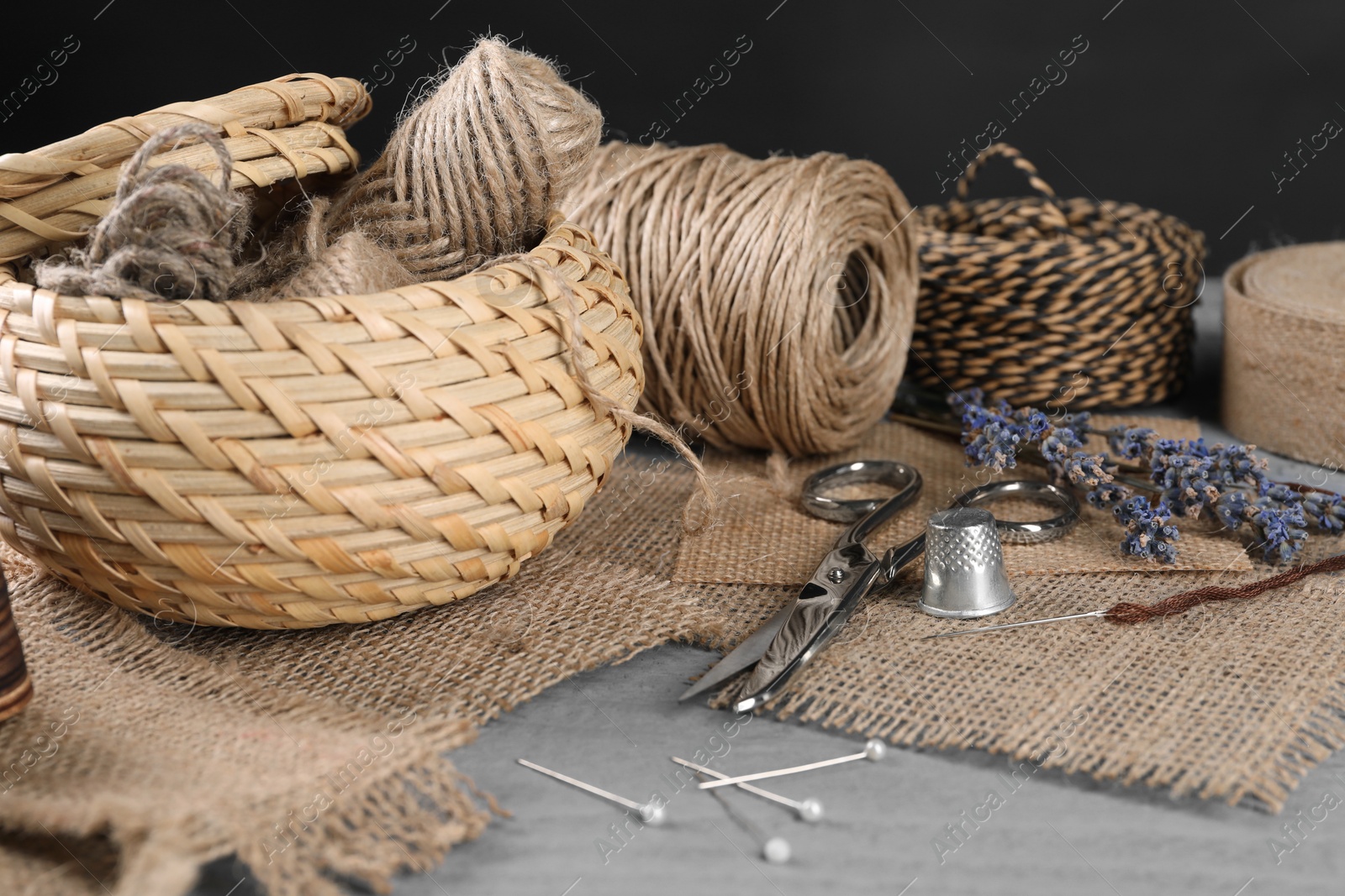 Photo of Pieces of burlap fabric and sewing tools on grey table