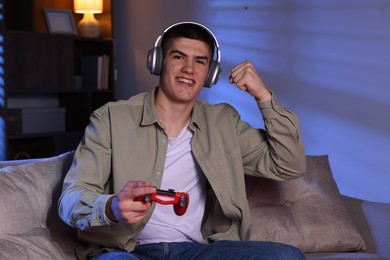 Photo of Emotional man playing video games with controller at home