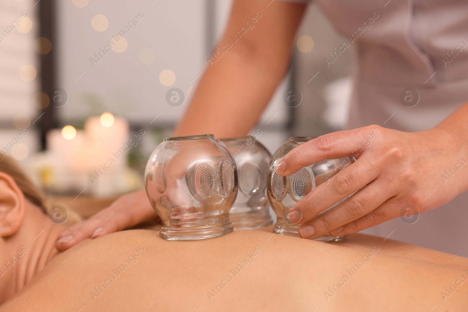Photo of Therapist giving cupping treatment to patient in spa salon, closeup