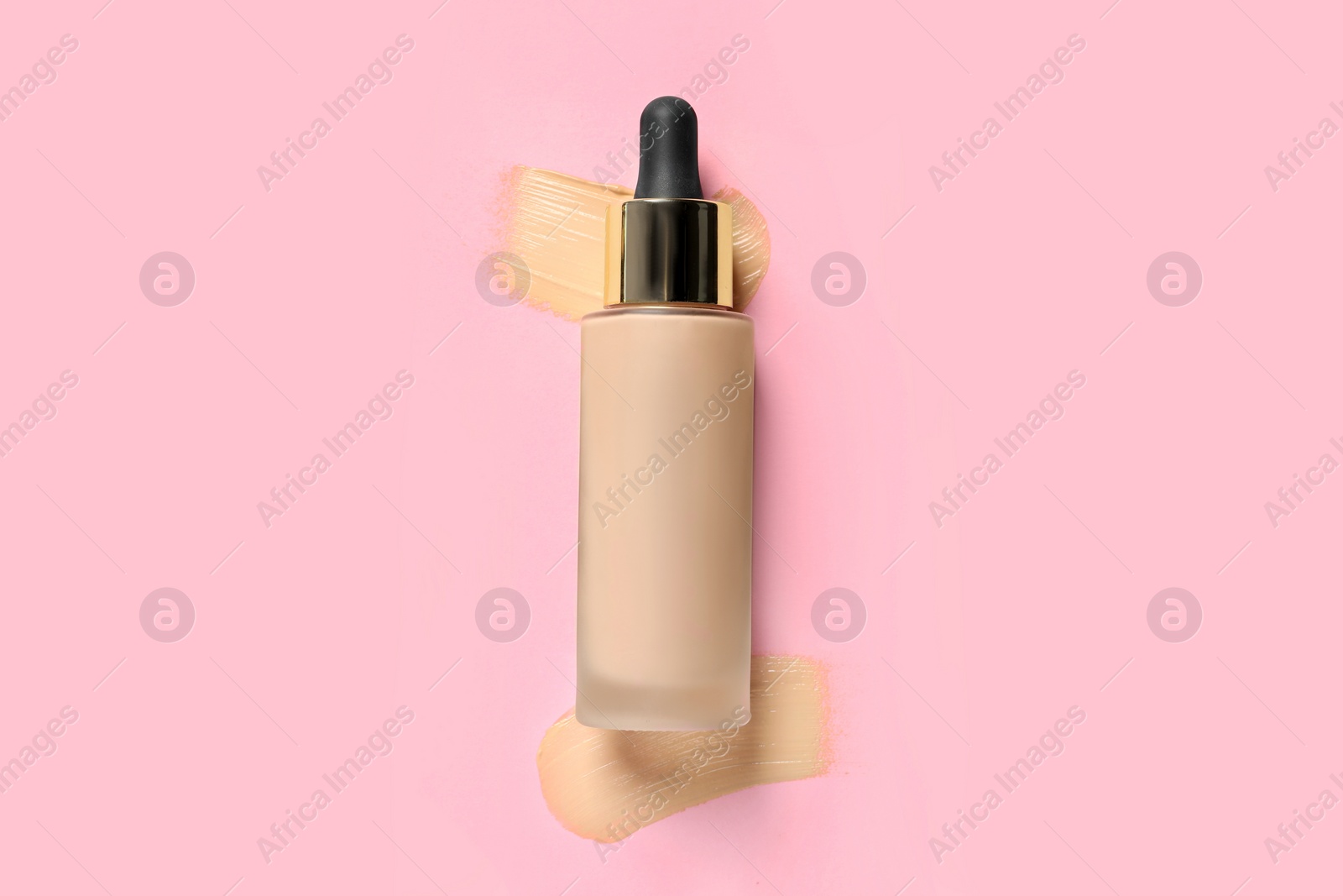 Photo of Liquid foundation and swatches on pink background, top view