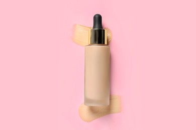 Photo of Liquid foundation and swatches on pink background, top view