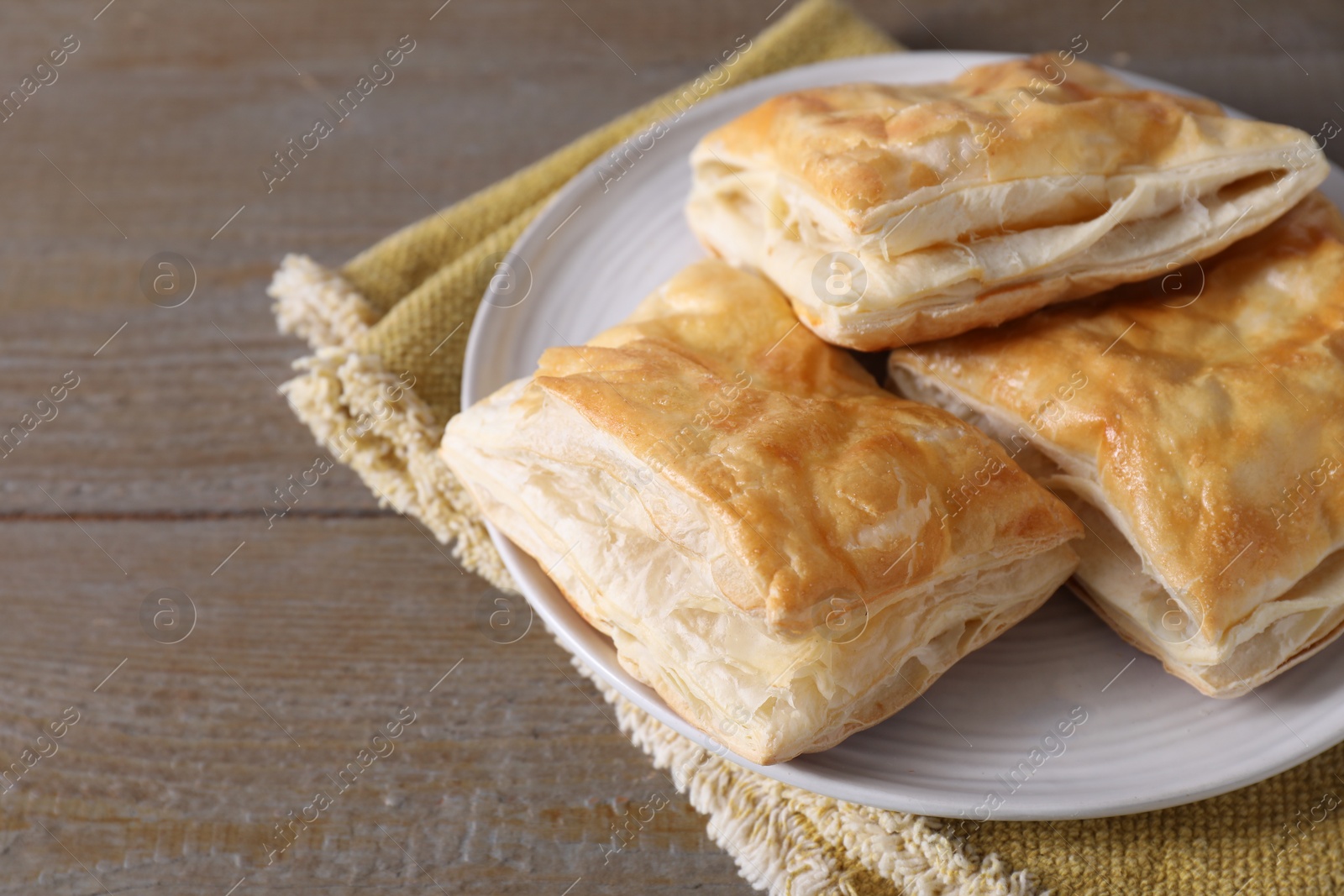 Photo of Delicious fresh puff pastries on wooden table, closeup. Space for text