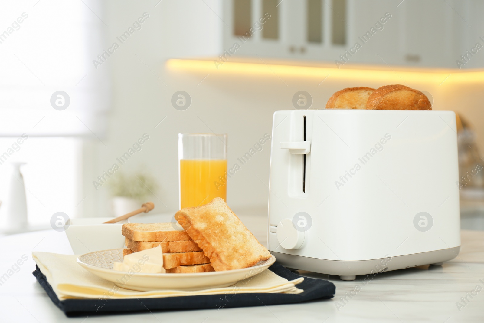 Photo of Modern toaster and tasty breakfast on white marble table in kitchen