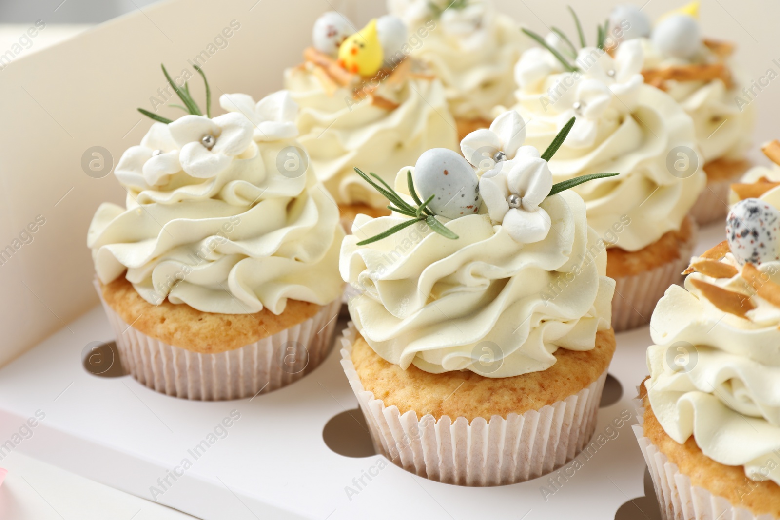 Photo of Tasty Easter cupcakes with vanilla cream in box, closeup