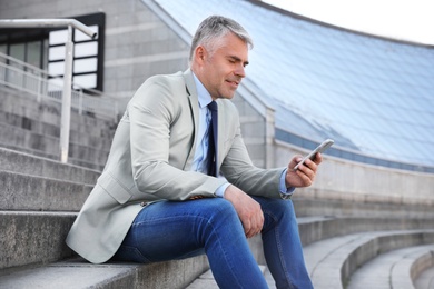 Photo of Portrait of handsome businessman with mobile phone in city