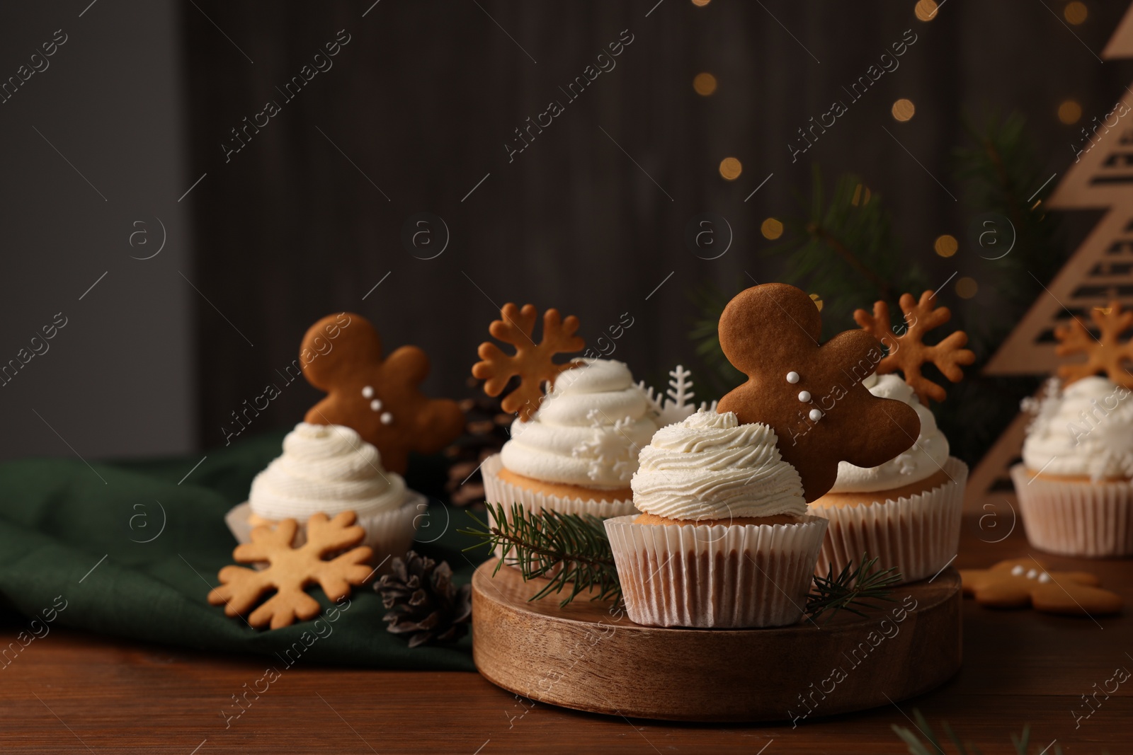 Photo of Different beautiful Christmas cupcakes and fir branches on wooden table. Space for text