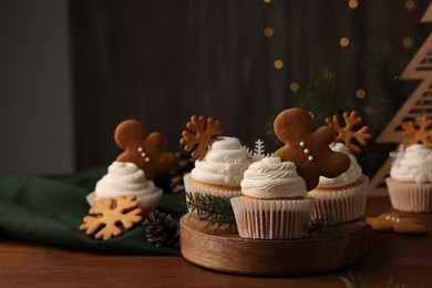 Different beautiful Christmas cupcakes and fir branches on wooden table. Space for text