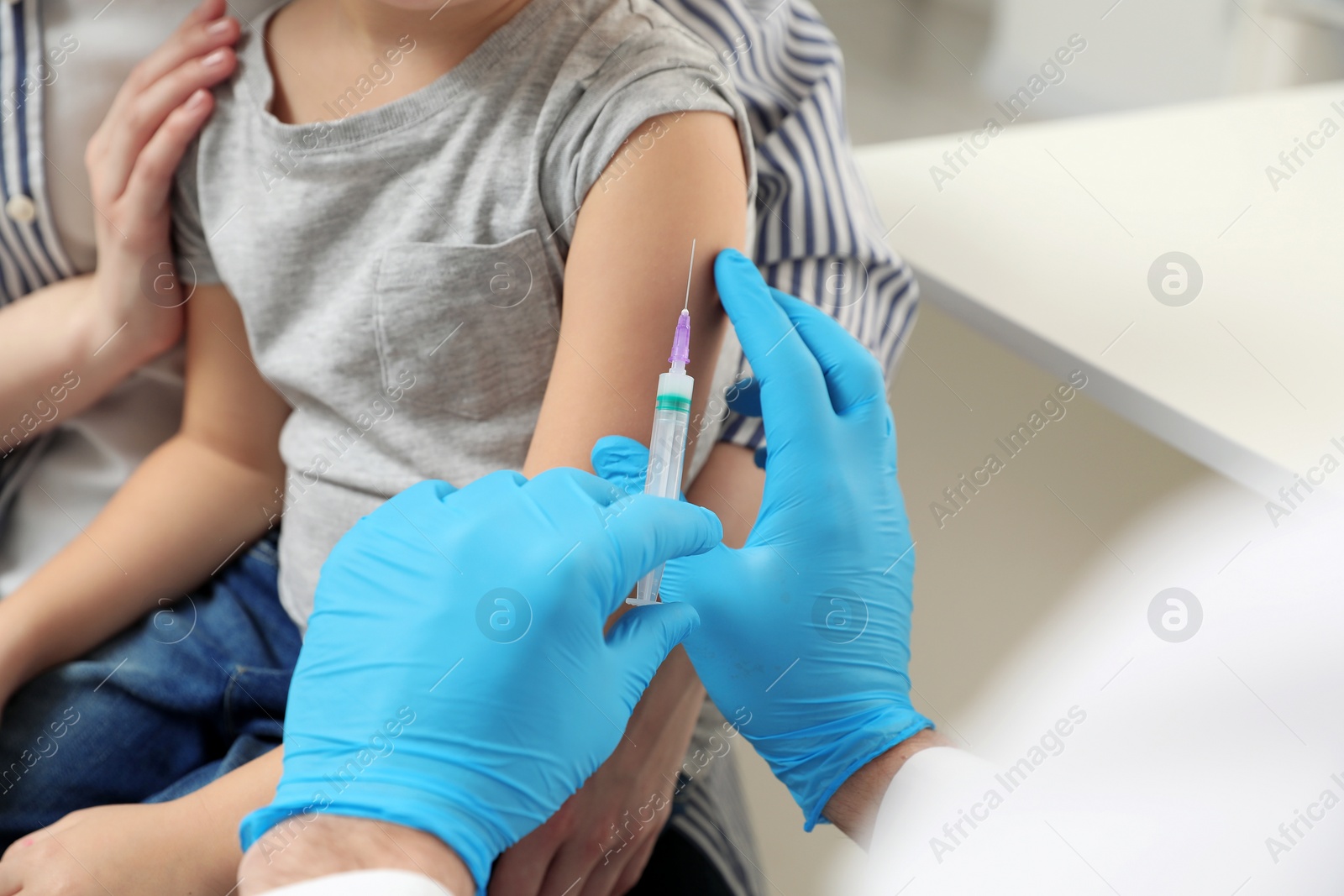 Photo of Children's hepatitis vaccination. Mother with her daughter in clinic. Doctor giving injection to little girl, closeup