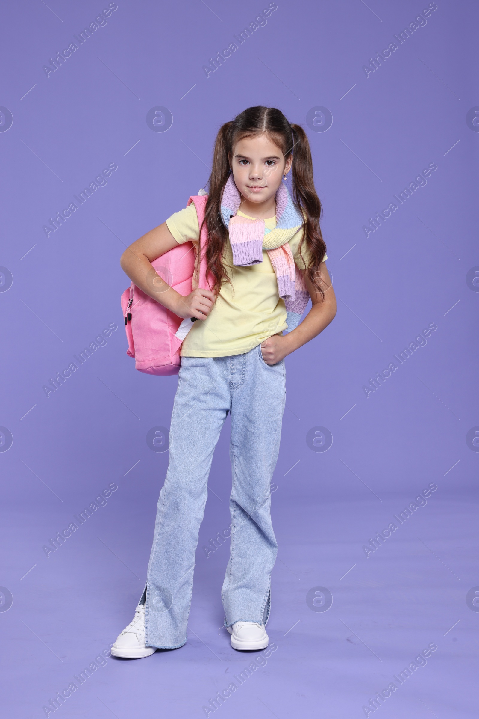 Photo of Back to school. Cute girl with backpack on violet background