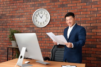 Happy boss holding documents in modern office