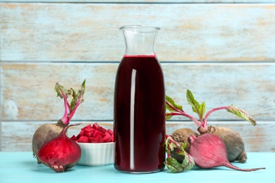 Photo of Fresh beet juice and raw vegetable on blue wooden table