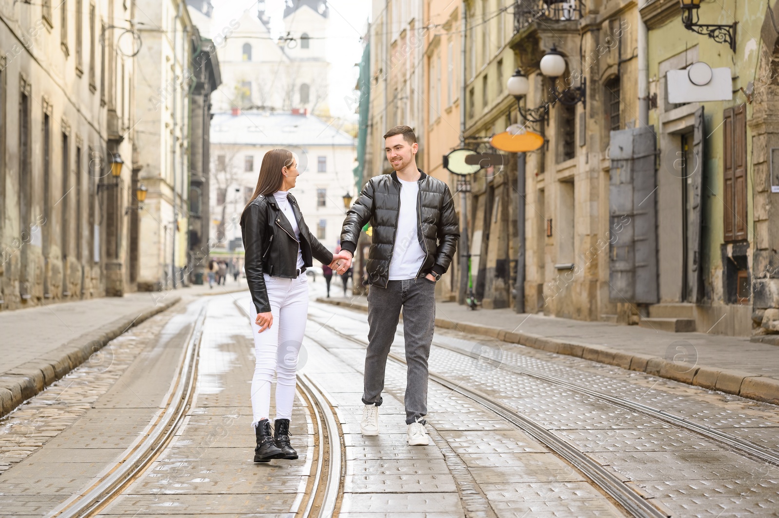 Photo of Lovely young couple walking along tram track on pavement road. Romantic date