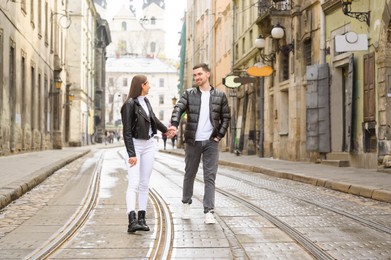 Photo of Lovely young couple walking along tram track on pavement road. Romantic date