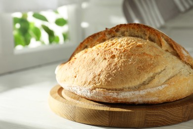 Freshly baked sourdough bread on white wooden table indoors. Space for text