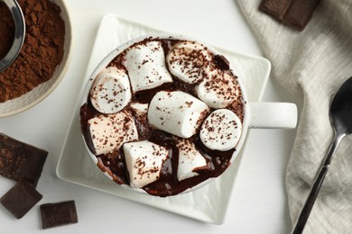 Delicious hot chocolate with marshmallows and cocoa powder in cup on white table, top view