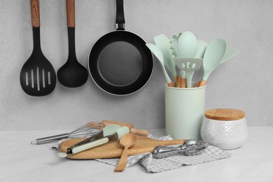 Photo of Set of different kitchen utensils on white near gray wall