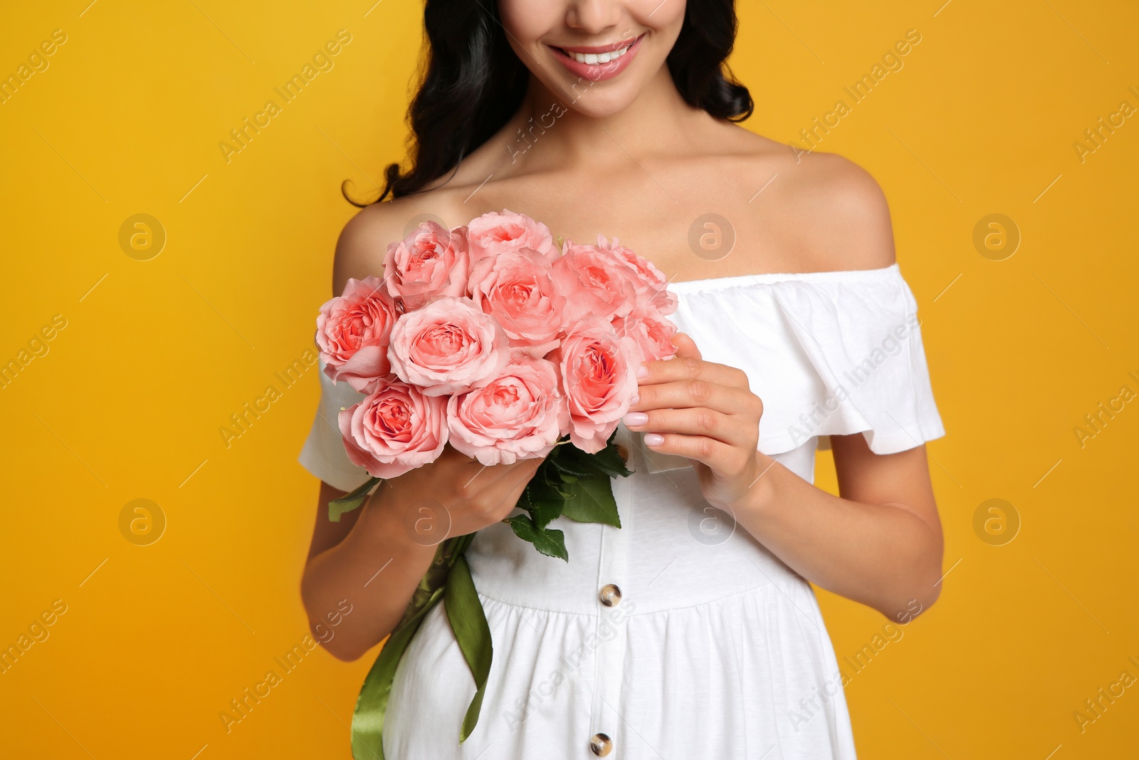 Photo of Young woman with beautiful bouquet on orange background, closeup