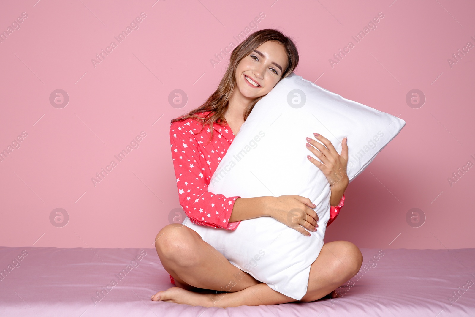 Photo of Beautiful teen girl hugging pillow on bed against color background