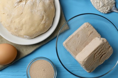 Different types of yeast, eggs, dough and flour on light blue wooden table, flat lay