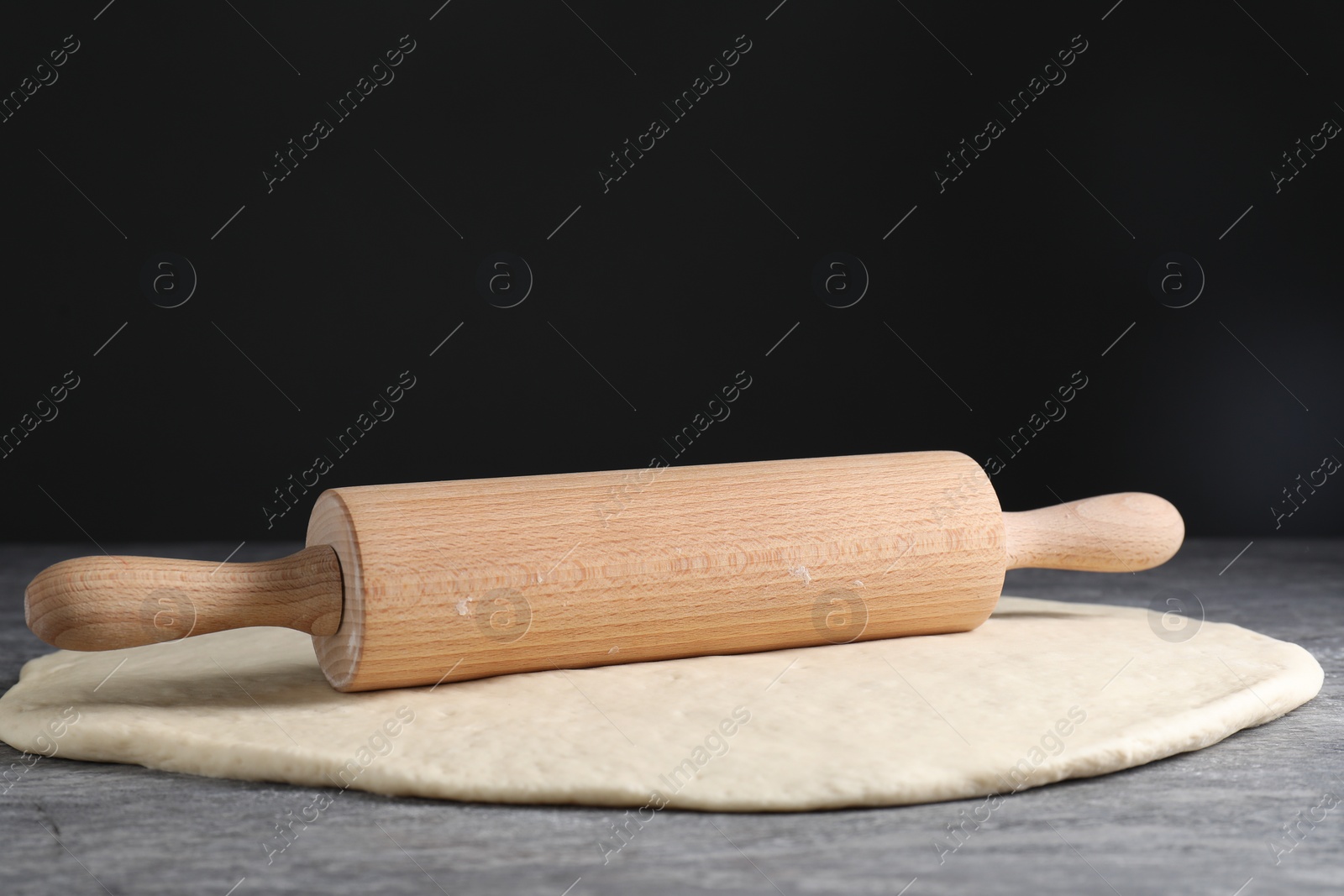 Photo of Raw dough and rolling pin on grey table