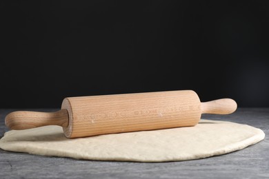 Raw dough and rolling pin on grey table