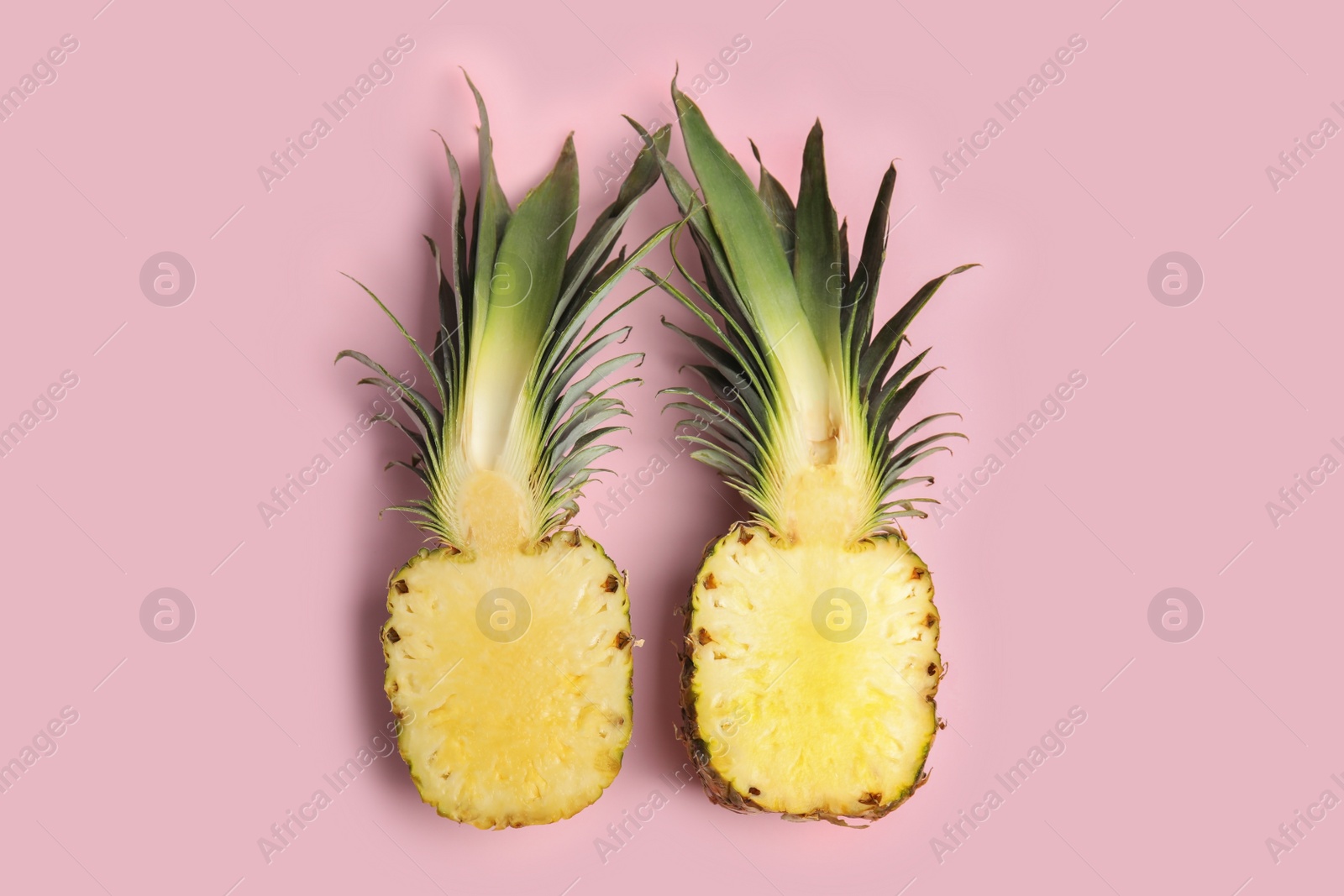 Photo of Halves of pineapple on pink background, flat lay