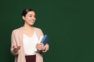 Photo of Portrait of young teacher with books on green background. Space for text