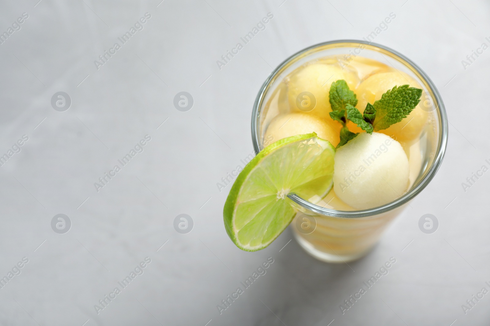 Photo of Glass of tasty melon ball drink on grey background with space for text