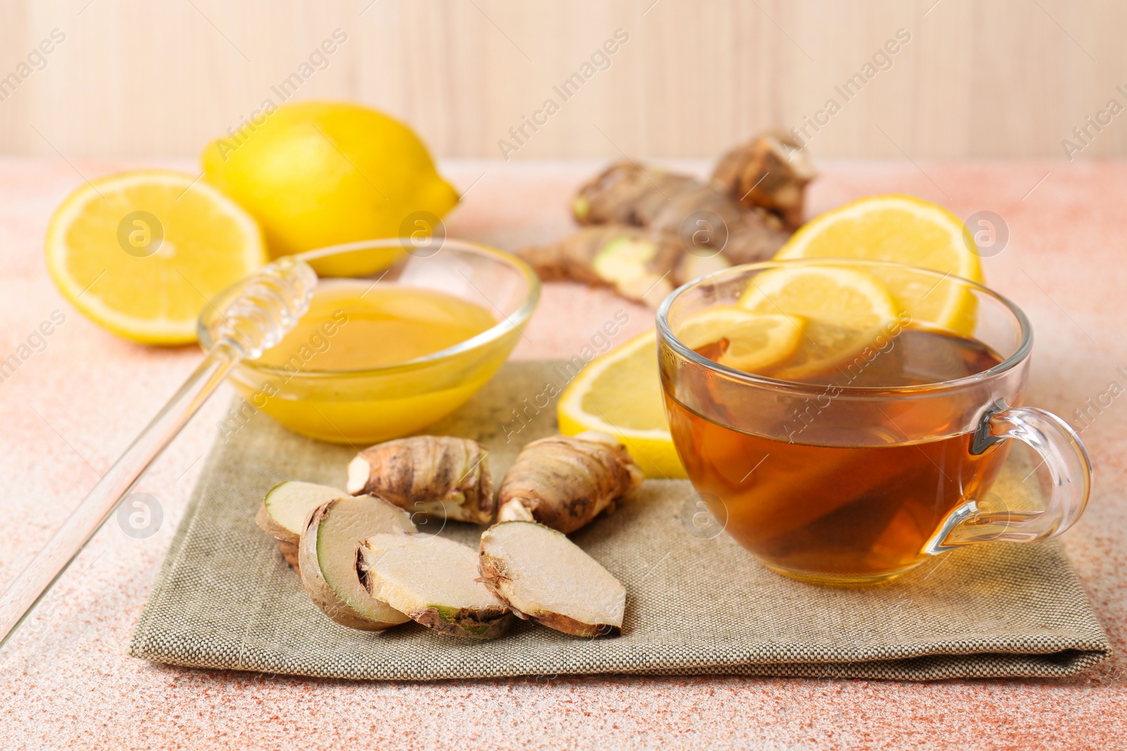 Photo of Tea, honey, lemon and ginger on beige textured table