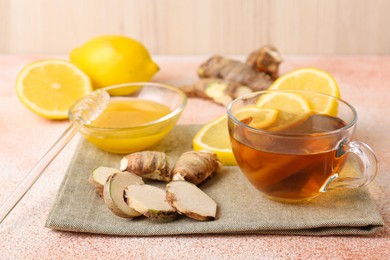 Photo of Tea, honey, lemon and ginger on beige textured table