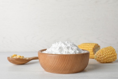 Bowl of corn starch and spoon with kernels on table