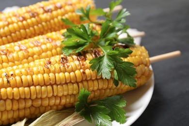 Tasty grilled corn on black table, closeup