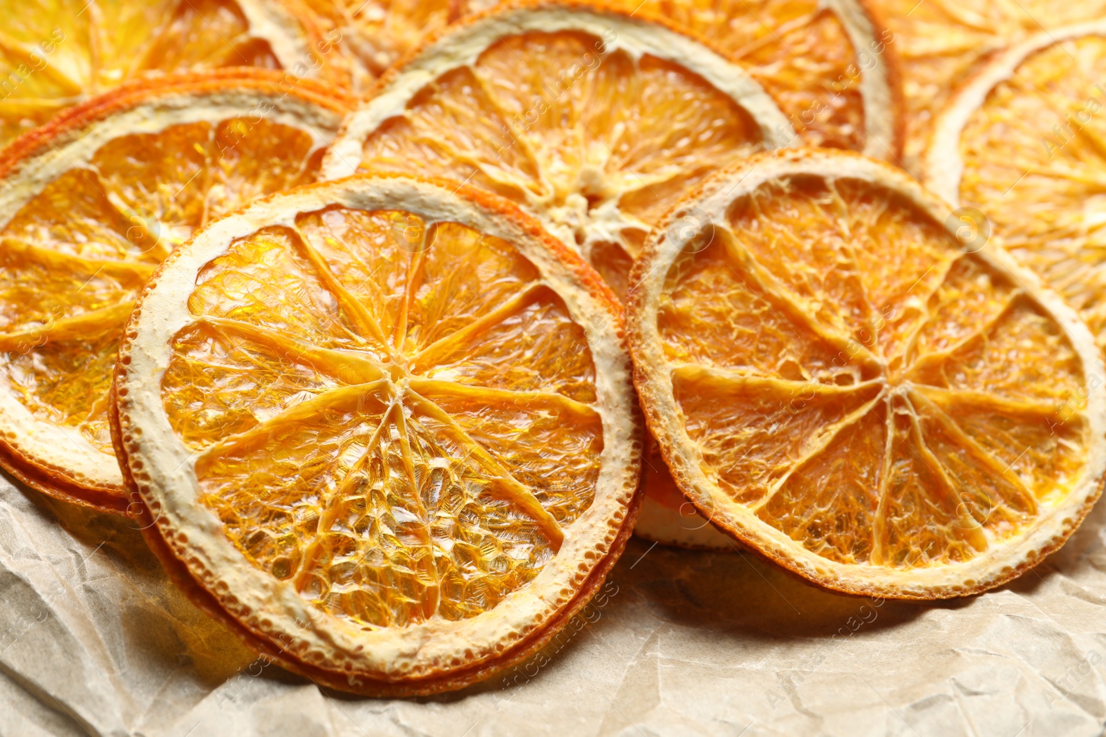 Photo of Many dry orange slices on parchment paper, closeup