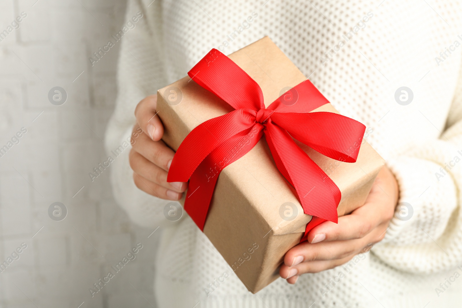 Photo of Young woman holding Christmas gift on light background, closeup