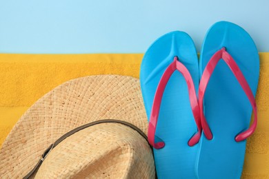 Photo of Flip flops, towel and hat on light blue background, flat lay. Beach accessories