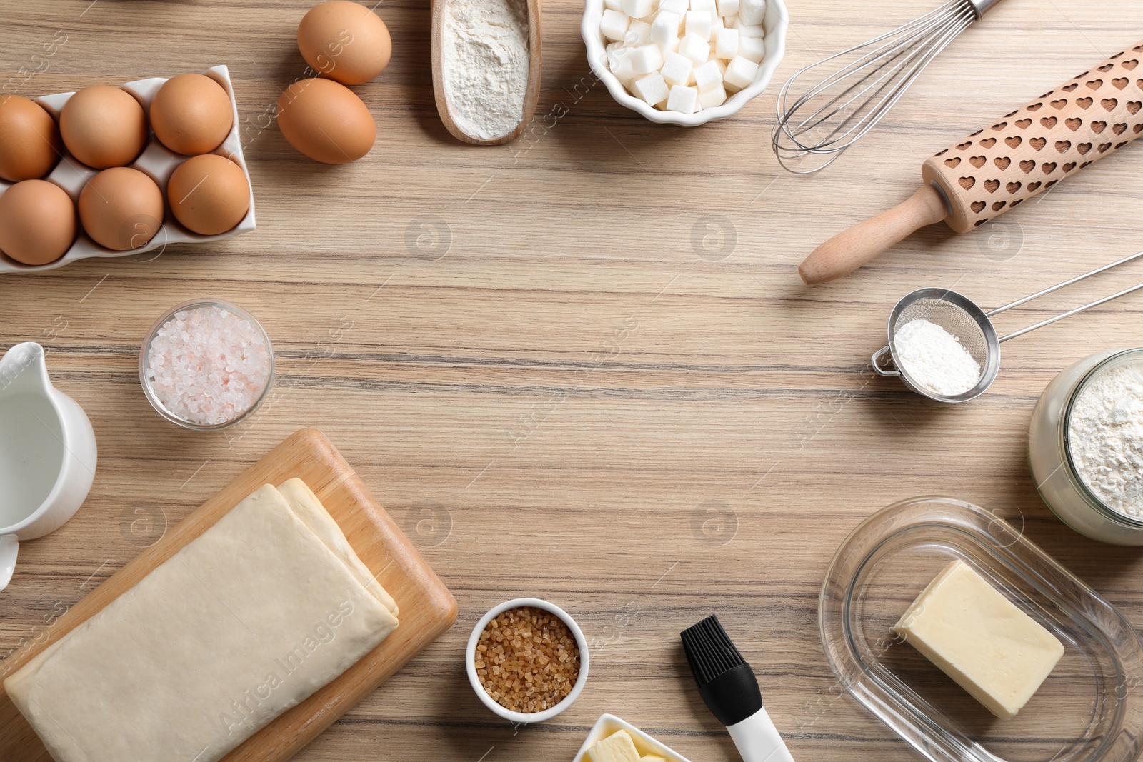 Photo of Frame made with puff pastry dough and ingredients on wooden table, flat lay. Space for text