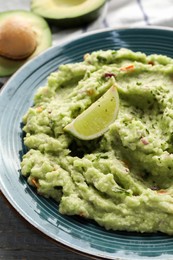 Photo of Delicious guacamole with lime on table, closeup