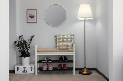 Photo of Stylish hallway room interior with bench, shoes and round mirror