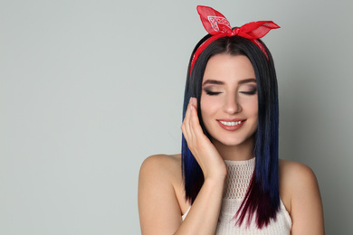 Photo of Young woman with bright dyed hair on light background