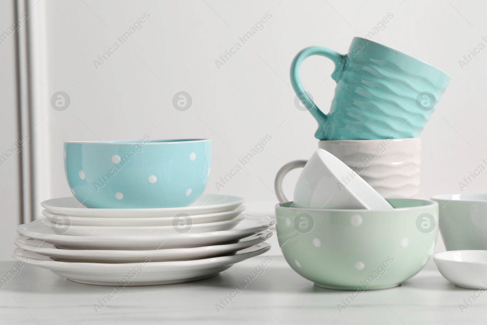 Photo of Beautiful ceramic dishware and cups on white marble table