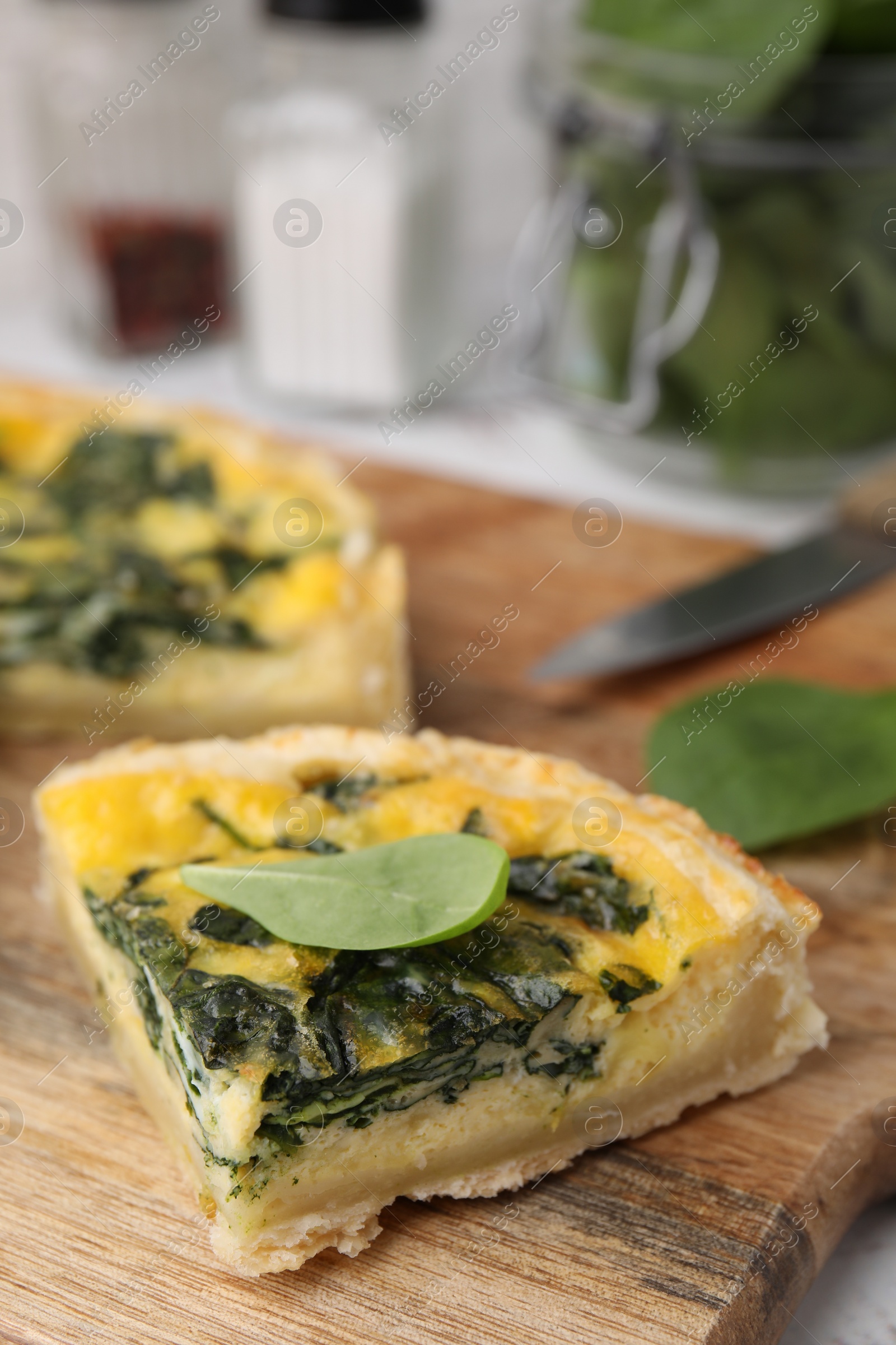 Photo of Piece of delicious pie with spinach on wooden board, closeup